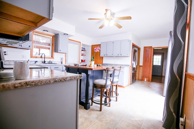 382 Keigwin Rd, Walnut, IL 61376 - kitchen with stainless steel refrigerator, fridge, a ceiling fan, wainscoting, and a breakfast bar area