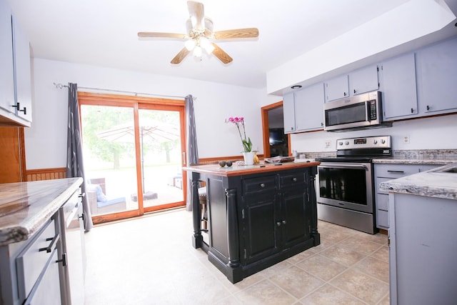 382 Keigwin Rd, Walnut, IL 61376 - kitchen with stainless steel appliances, ceiling fan, a kitchen island, dark cabinetry, and light stone counters