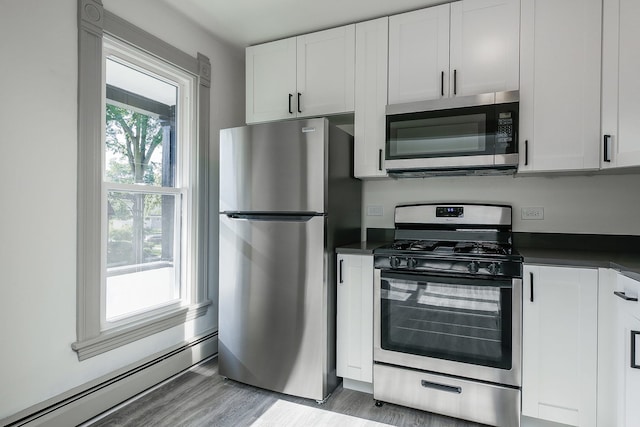 123 N W St, Wheaton, IL 60187 - kitchen with stainless steel appliances, a baseboard radiator, dark countertops, light wood-style flooring, and white cabinets
