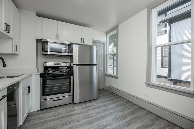 123 N W St, Wheaton, IL 60187 - kitchen with stainless steel appliances, a baseboard heating unit, white cabinets, and light countertops