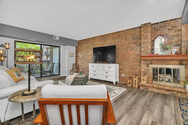 1422 Woodbridge Rd Unit 2E, Joliet, IL 60436 - living room featuring a textured ceiling, wood finished floors, a brick fireplace, and brick wall