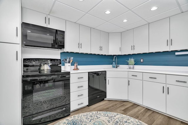 1422 Woodbridge Rd Unit 2E, Joliet, IL 60436 - kitchen featuring black appliances, light wood-style floors, light countertops, white cabinets, and a drop ceiling