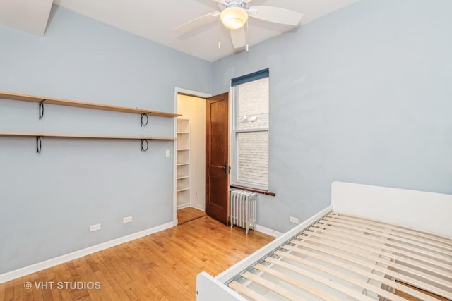 1133 N Spaulding Ave, Chicago, IL 60651 - unfurnished bedroom with radiator, light wood-style flooring, and a ceiling fan