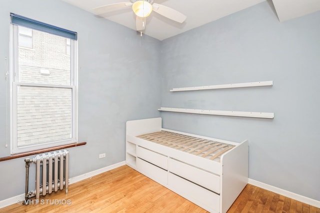 1133 N Spaulding Ave, Chicago, IL 60651 - unfurnished bedroom with radiator, wood finished floors, and ceiling fan