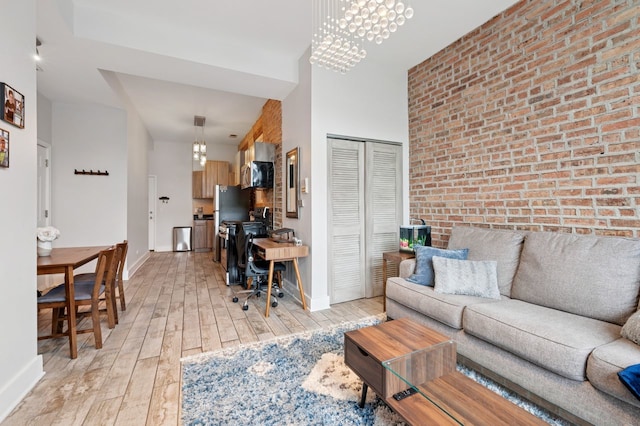 1423 N Ashland Ave Unit 201, Chicago, IL 60622 - living room with a chandelier, brick wall, light wood-style flooring, a towering ceiling, and a desk