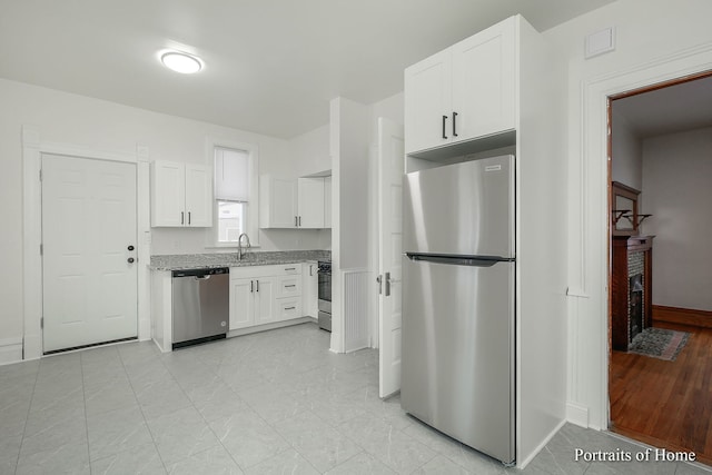 127 N W St, Wheaton, IL 60187 - kitchen with stainless steel appliances, a brick fireplace, white cabinetry, light stone countertops, and light tile patterned floors