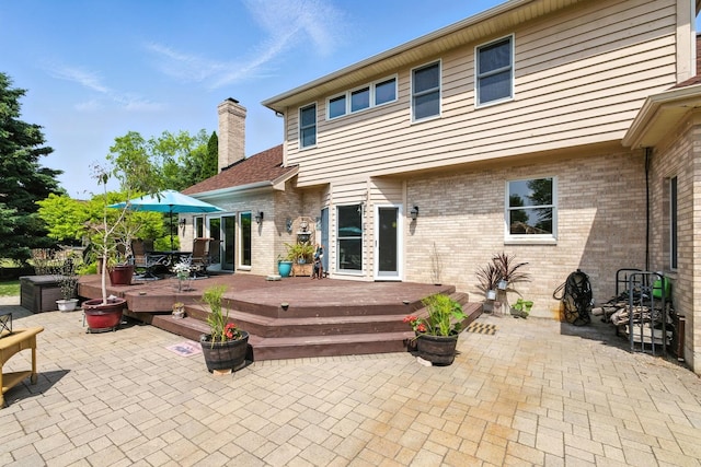 14N924 White Pines Ln, Hampshire, IL 60140 - back of property with a patio, a wooden deck, a chimney, and brick siding