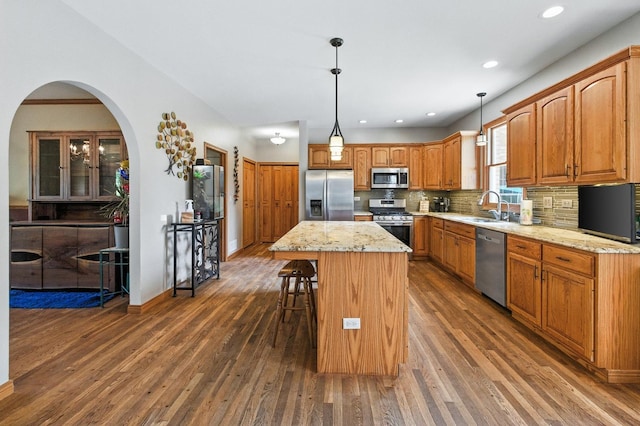 14N924 White Pines Ln, Hampshire, IL 60140 - kitchen featuring appliances with stainless steel finishes, dark wood-style floors, a kitchen island, decorative backsplash, and a breakfast bar area