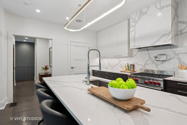 417 E N Water St, Chicago, IL 60611 - kitchen featuring high end stove, white cabinetry, decorative backsplash, wall chimney range hood, and recessed lighting