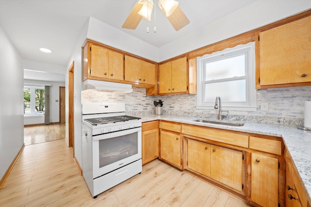 2317 W 50th St, Chicago, IL 60609 - kitchen featuring white range with gas cooktop, under cabinet range hood, light wood-type flooring, backsplash, and a ceiling fan