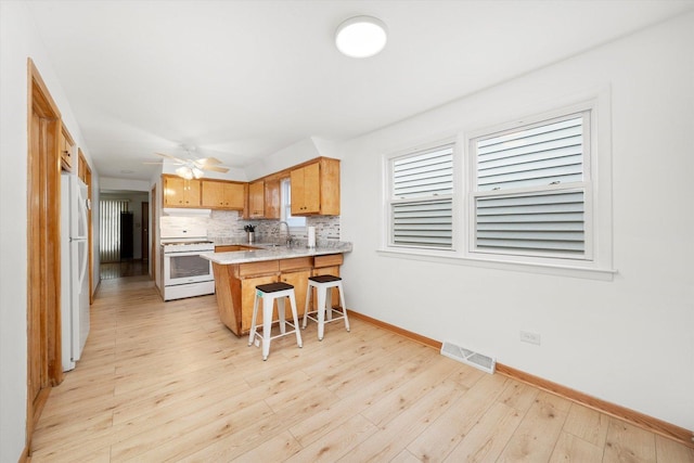 2317 W 50th St, Chicago, IL 60609 - kitchen with white appliances, a peninsula, tasteful backsplash, light countertops, and light wood-type flooring