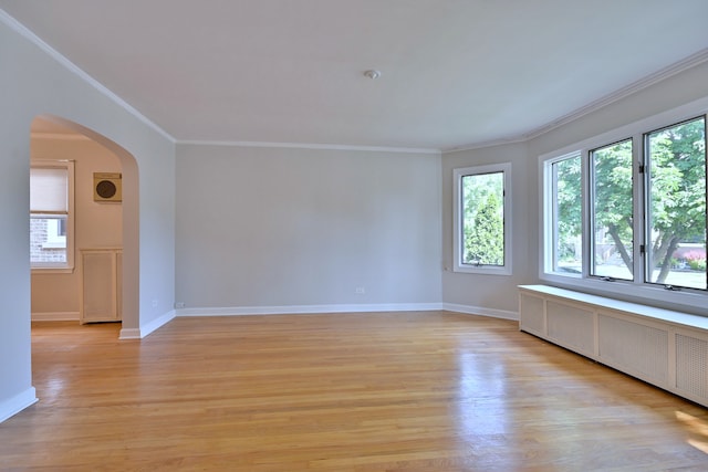 7851 W Cressett Dr, Elmwood Park, IL 60707 - spare room featuring radiator, arched walkways, crown molding, and light wood-style flooring