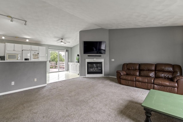 6072 Nimtz Ct, Loves Park, IL 61111 - carpeted living room with ceiling fan, a glass covered fireplace, vaulted ceiling, a textured ceiling, and track lighting