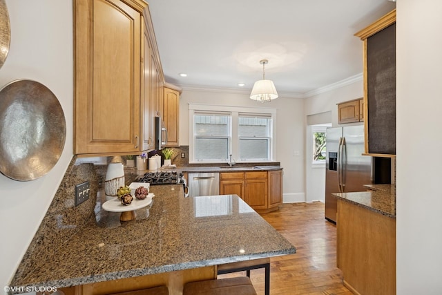 4628 Grand Ave, Western Springs, IL 60558 - kitchen with stainless steel appliances, a kitchen breakfast bar, light wood-style flooring, ornamental molding, and dark stone countertops