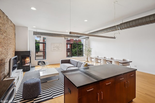 1525 N Milwaukee Ave Unit 3, Chicago, IL 60622 - kitchen featuring light wood finished floors, dark countertops, a kitchen island, a lit fireplace, and open floor plan