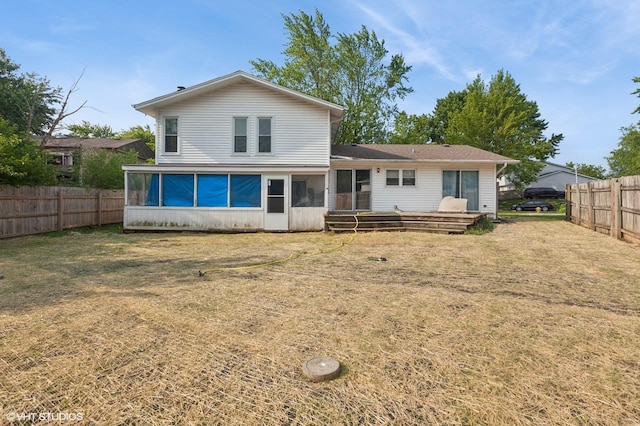 back of property with a sunroom, a fenced backyard, and a deck