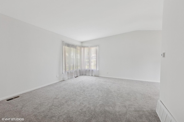 carpeted empty room featuring lofted ceiling and baseboards