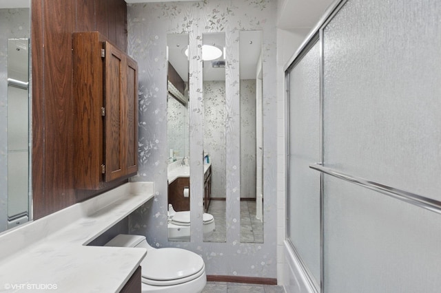 bathroom with wallpapered walls, vanity, and shower / bath combination with glass door