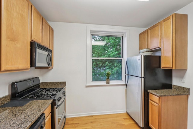820 Washington Blvd Unit 3, Oak Park, IL 60302 - kitchen featuring black microwave, range with gas stovetop, freestanding refrigerator, light wood-type flooring, and dark stone countertops