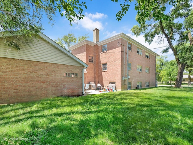 6737 W Lloyd Dr, Worth, IL 60482 - rear view of house featuring a chimney, a lawn, a patio area, and brick siding