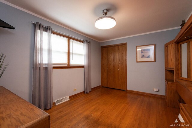 7707 Moody Ave, Burbank, IL 60459 - unfurnished bedroom with light wood finished floors, ornamental molding, and a closet