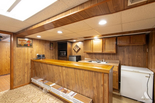 7707 Moody Ave, Burbank, IL 60459 - kitchen featuring refrigerator, black microwave, wooden walls, brown cabinets, and freestanding refrigerator