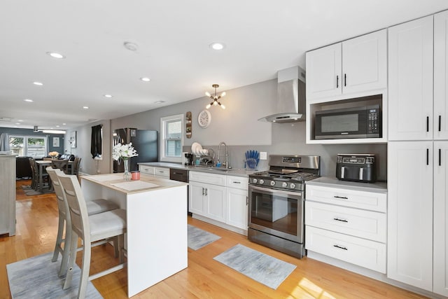 1715 N 15th Ave, Melrose Park, IL 60160 - kitchen featuring appliances with stainless steel finishes, wall chimney exhaust hood, healthy amount of natural light, white cabinetry, and recessed lighting