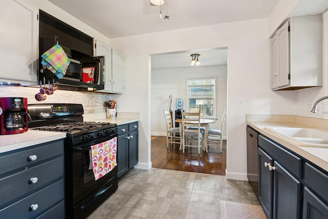 kitchen featuring black range with gas cooktop, light countertops, tasteful backsplash, and wood finished floors