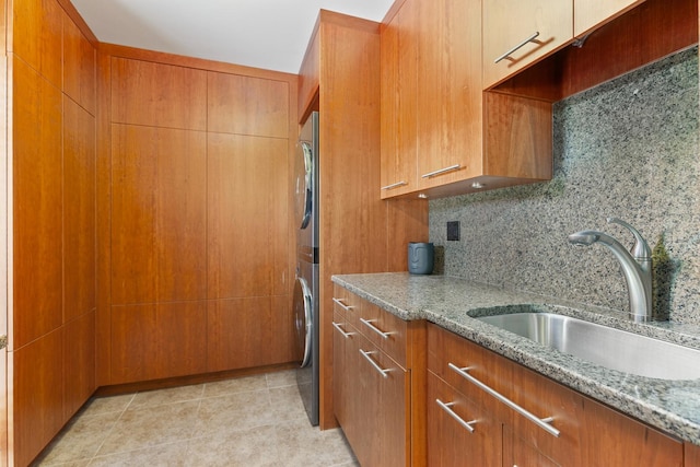 1200 Regency Ln, Lake Forest, IL 60045 - kitchen with light stone counters, brown cabinets, estacked washer and dryer, and decorative backsplash