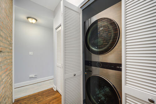 4259 N Ashland Ave Unit 2, Chicago, IL 60613 - laundry area with stacked washer and clothes dryer and wood finished floors