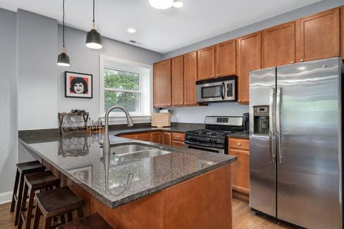 4259 N Ashland Ave Unit 2, Chicago, IL 60613 - kitchen featuring appliances with stainless steel finishes, brown cabinets, a peninsula, a kitchen bar, and recessed lighting