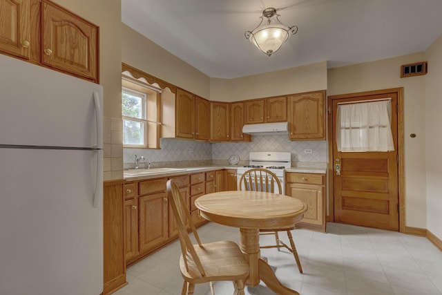 4934 N Marmora Ave, Chicago, IL 60630 - kitchen with white appliances, under cabinet range hood, light countertops, decorative backsplash, and brown cabinetry