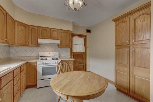 4934 N Marmora Ave, Chicago, IL 60630 - kitchen with white range with gas cooktop, under cabinet range hood, light countertops, and decorative backsplash