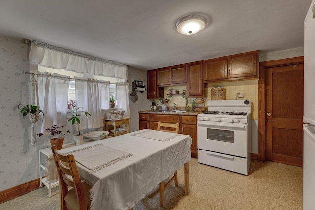4934 N Marmora Ave, Chicago, IL 60630 - kitchen featuring white range with gas stovetop, wallpapered walls, brown cabinets, and backsplash