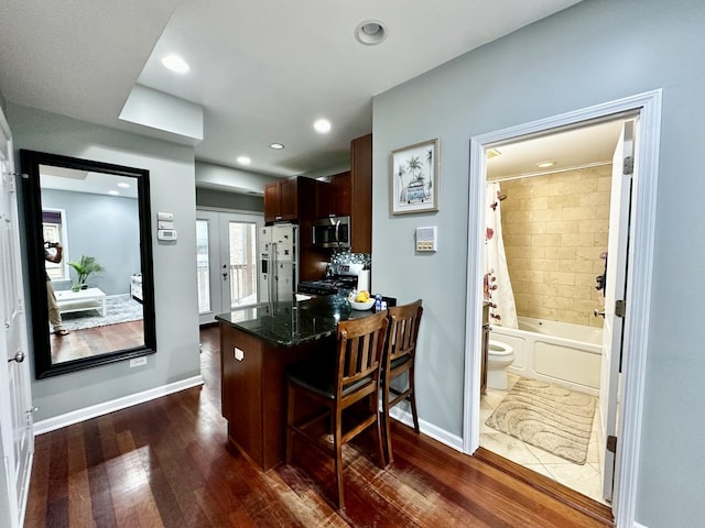 1366 W Greenleaf Ave Unit 3N, Chicago, IL 60626 - kitchen with stainless steel microwave, white refrigerator with ice dispenser, gas stove, a kitchen breakfast bar, and dark wood-style flooring