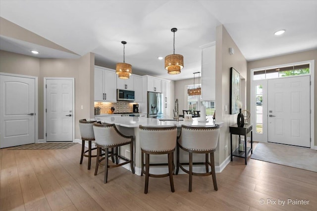 2213 Tyler Trl, Mchenry, IL 60051 - kitchen featuring stainless steel appliances, a breakfast bar area, white cabinets, light wood finished floors, and recessed lighting