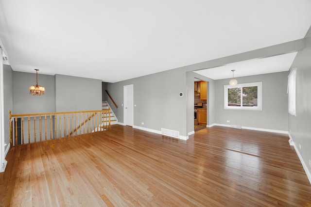 220 N Yates Ln, Mount Prospect, IL 60056 - unfurnished room featuring light wood-type flooring, a chandelier, and stairway