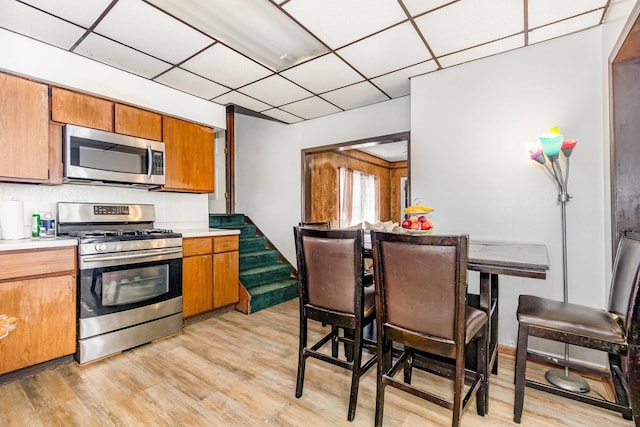 408 Summit St, Joliet, IL 60435 - kitchen with appliances with stainless steel finishes, a paneled ceiling, light wood-style flooring, brown cabinets, and light countertops