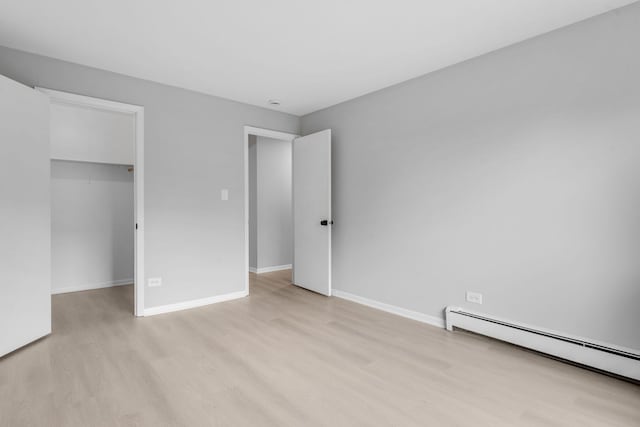 1195 Meadow Ln Unit 213, Hoffman Estates, IL 60169 - unfurnished bedroom with a baseboard heating unit, a walk in closet, and light wood-style flooring