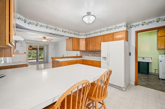 115 Fair St, Sycamore, IL 60178 - kitchen featuring white refrigerator with ice dispenser, a peninsula, washer / clothes dryer, light countertops, and brown cabinets