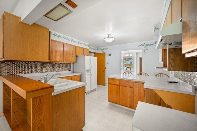 115 Fair St, Sycamore, IL 60178 - kitchen featuring white fridge with ice dispenser, under cabinet range hood, a peninsula, light flooring, and backsplash