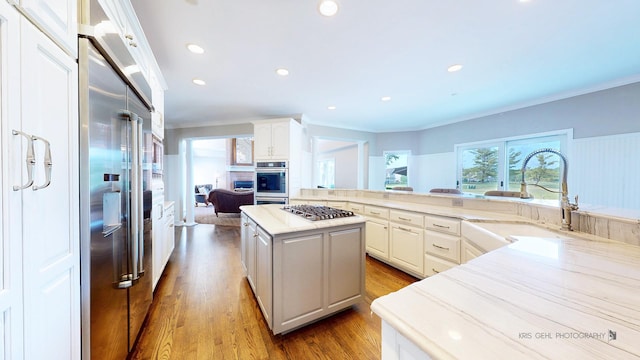 2520 Hanford Ln, Aurora, IL 60502 - kitchen featuring appliances with stainless steel finishes, ornamental molding, white cabinets, wood finished floors, and a kitchen island