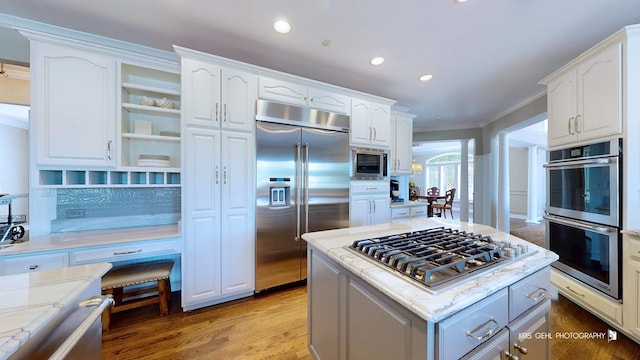 2520 Hanford Ln, Aurora, IL 60502 - kitchen featuring built in appliances, ornamental molding, white cabinets, light stone counters, and light wood-type flooring