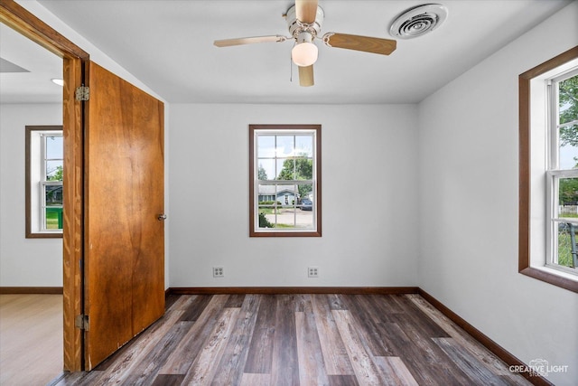 812 S Sumner Ave, Aurora, IL 60505 - unfurnished bedroom with multiple windows, dark wood finished floors, and a ceiling fan