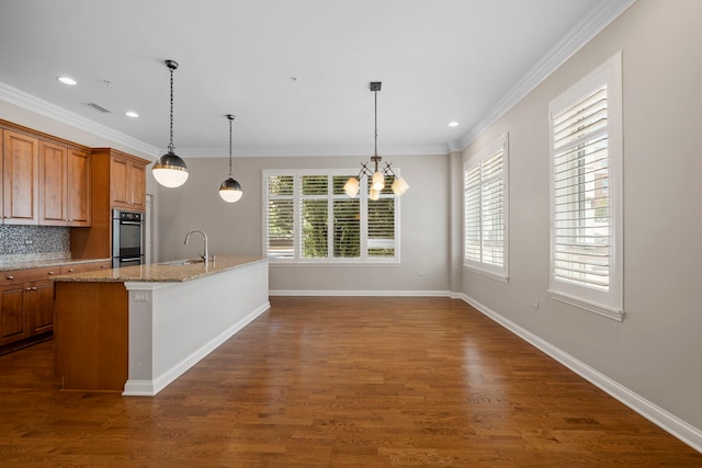1000 Village Center Dr Unit 103, Burr Ridge, IL 60527 - kitchen featuring brown cabinets, dark wood-style floors, crown molding, light stone counters, and a center island with sink