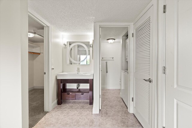 920 Vose Dr Unit 612, Gurnee, IL 60031 - bathroom with a textured ceiling, stacked washing machine and dryer, a closet, tile patterned flooring, and vanity