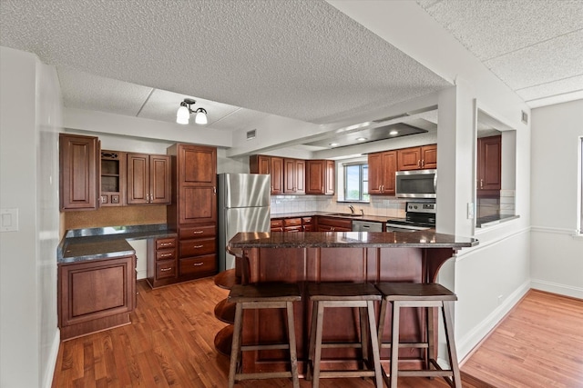 920 Vose Dr Unit 612, Gurnee, IL 60031 - kitchen featuring stainless steel appliances, a breakfast bar, light wood-style flooring, a textured ceiling, and backsplash