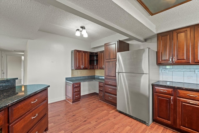 920 Vose Dr Unit 612, Gurnee, IL 60031 - kitchen featuring freestanding refrigerator, light wood-style floors, a textured ceiling, backsplash, and dark stone counters