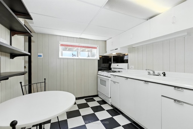 3219 N Pioneer Ave, Chicago, IL 60634 - kitchen with gas range gas stove, tile patterned floors, under cabinet range hood, white cabinets, and wood walls