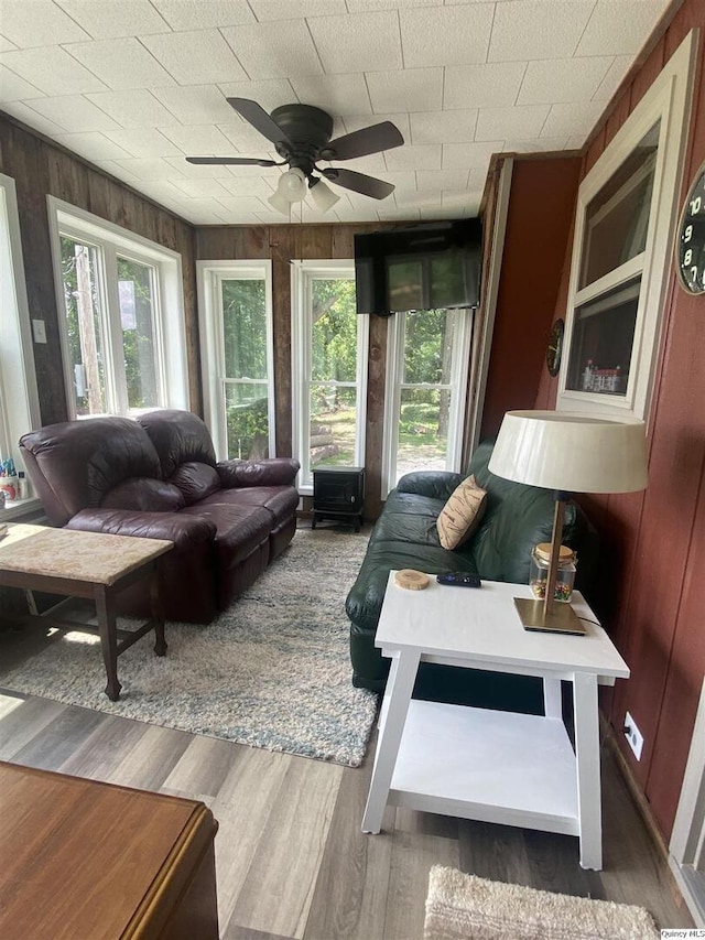 110 E County Rd 150, Warsaw, IL 62379 - living room featuring healthy amount of natural light, a ceiling fan, wood walls, and wood finished floors